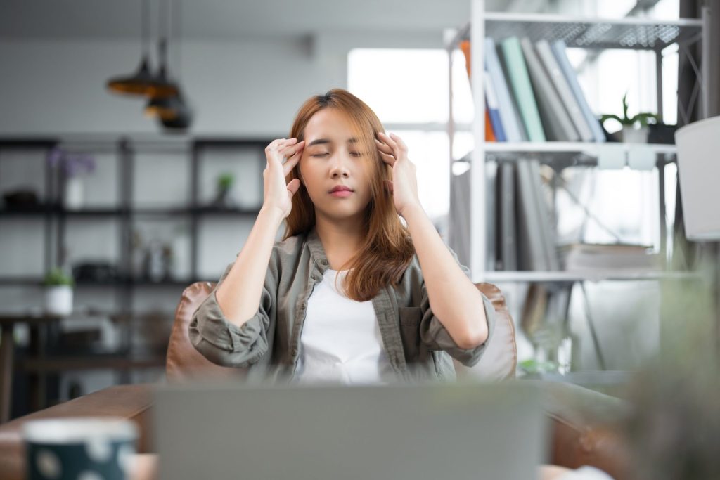 Woman overworked and exhausted experiences headaches and vision issues after using a laptop for work